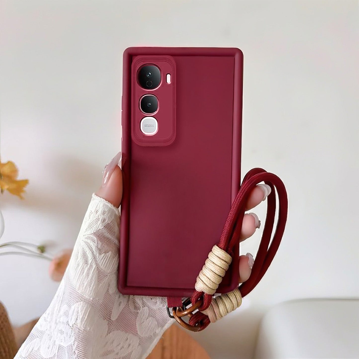 Red phone case with a strap held by a hand against a light background